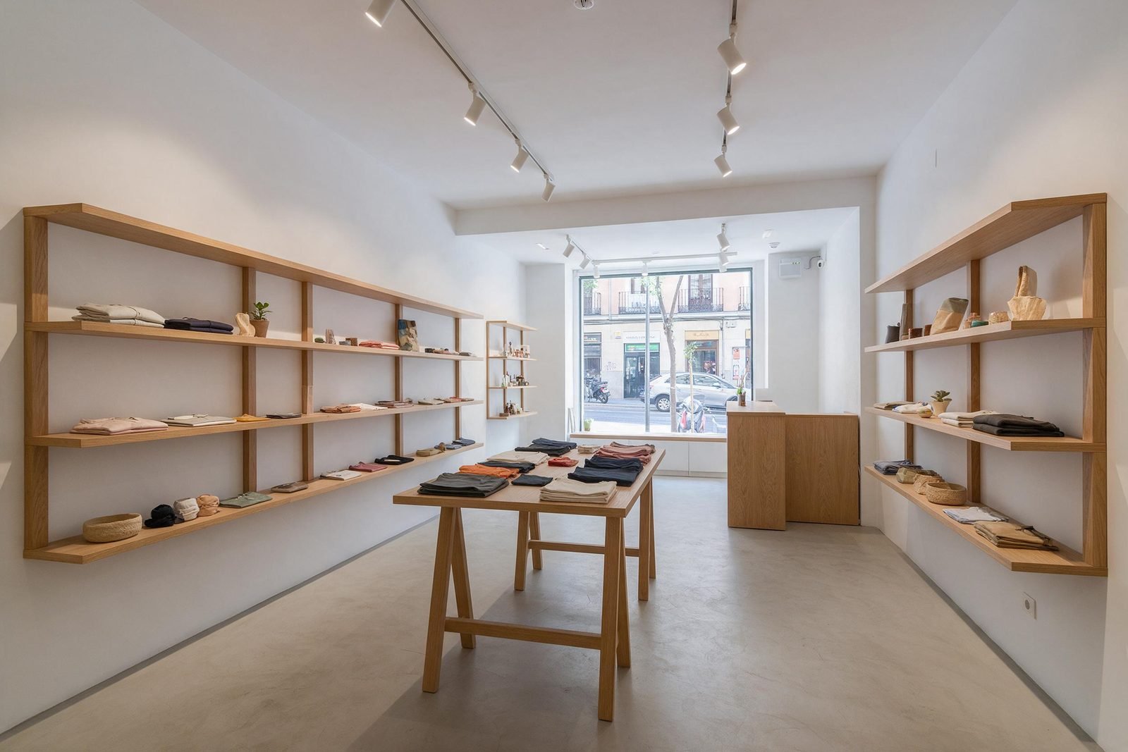 Tienda reformada en Madrid con estanterías de roble, suelo de microcemento y escaparate a la calle